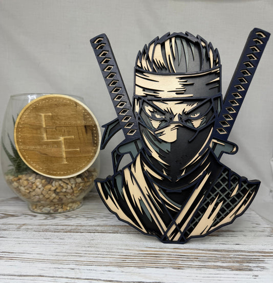 A laser-cut wooden decorative figurine of a ninja warrior with two crossed swords, made from colored wood from Etched in Favour. 